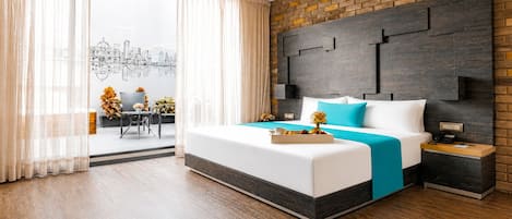 Una habitación de hotel moderna con una cama grande, vistas a la ciudad, una pared decorativa de ladrillo y un balcón con comedor.