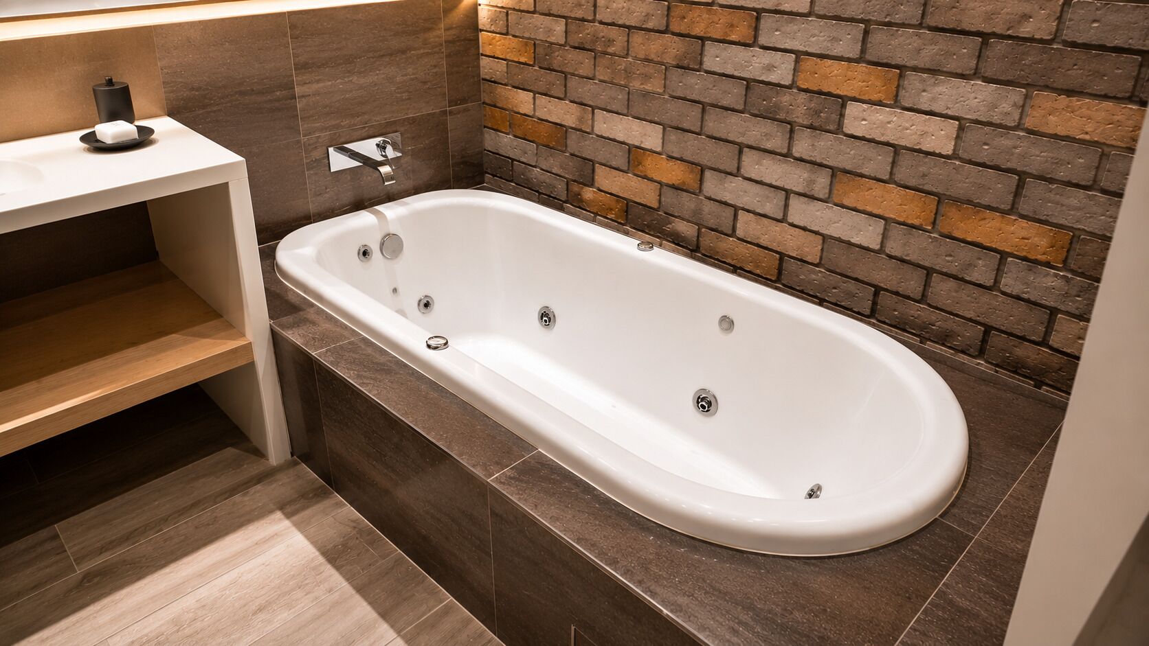 A modern bathroom with a freestanding bathtub, a wooden shelf, and a brick-patterned wall.