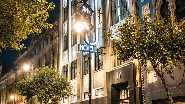 Een hotel met een opvallend bord, een geplaveid straatje en klassieke architectuur.