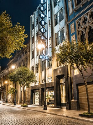 Un hôtel reconnaissable à son enseigne imposante, situé dans une rue pavée et doté d’une architecture classique.