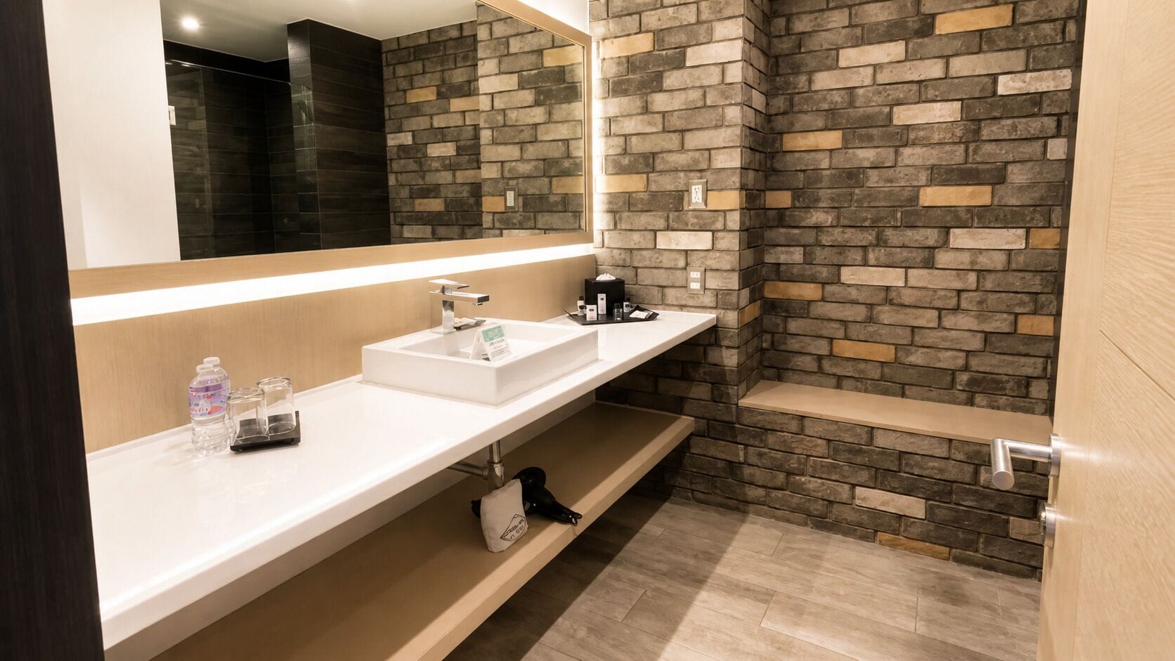 Ein modernes Badezimmer mit einem weißen Waschbecken, einem Spiegel und einer Duschkabine mit Steinwand.
