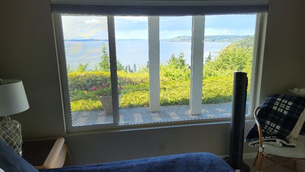 A bedroom with a large window offering a view of a lake and greenery. - Island View-Spectacular view of Puget Sound and the Olympic Mountains (Burien)