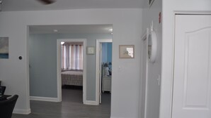 Ein Flur mit einem Bett, einem Nachttisch und einer Tür zu einem anderen Zimmer.