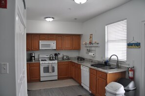 A kitchen with wooden cabinets, a microwave, stove, sink, and a fire extinguisher.