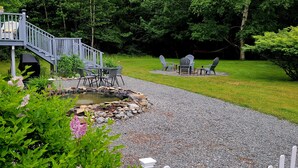 A house with a deck, outdoor seating, and a garden with a pond. - Quiet location. Home is 1/2 a mile to Seawall Beach and 3 miles to town center. (Southwest Harbor)