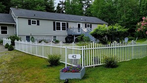 A two-story house with a white picket fence, a number 42 sign, and a flower bed in front. - Quiet location. Home is 1/2 a mile to Seawall Beach and 3 miles to town center. (Southwest Harbor)