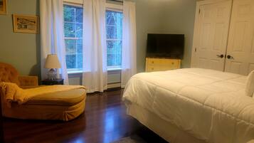 A bedroom with a bed, a chair, a TV, and a dresser.