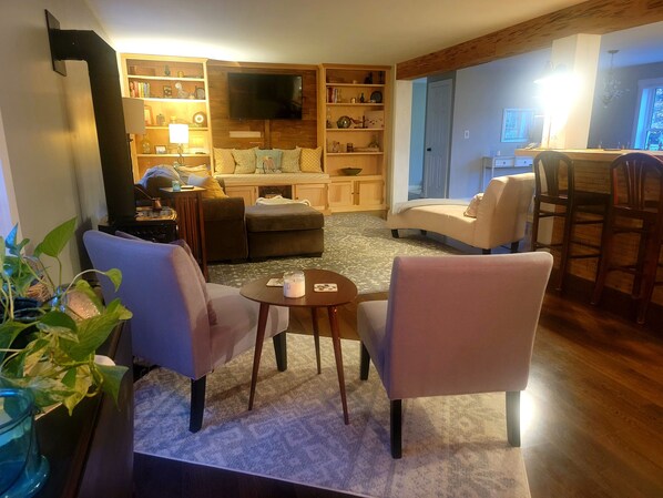 A cozy living room with a fireplace, comfortable seating, a television, and a bookshelf. - Quiet location. Home is 1/2 a mile to Seawall Beach and 3 miles to town center. (Southwest Harbor)