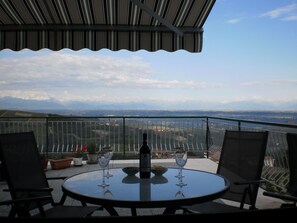 Un balcon avec une table, deux chaises, une bouteille et deux verres à vin.