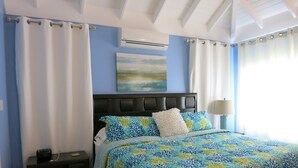 A bedroom with a bed, nightstand, lamp, and artwork on the wall.