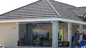 A covered outdoor area with a pool, exercise equipment, and a sign indicating no wet attire allowed.