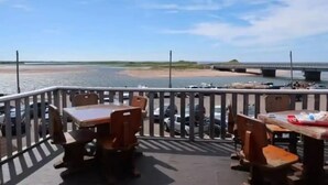 A deck with wooden tables and chairs overlooking a body of water and a bridge. - Beach, Golf, Relax & Enjoy Our Beautiful Stanhope, PEI Cottage for your vacation (Stanhope)