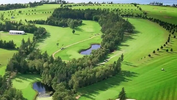 An aerial view of a golf course with a clubhouse, water hazards, and surrounding greenery. - Beach, Golf, Relax & Enjoy Our Beautiful Stanhope, PEI Cottage for your vacation (Stanhope)