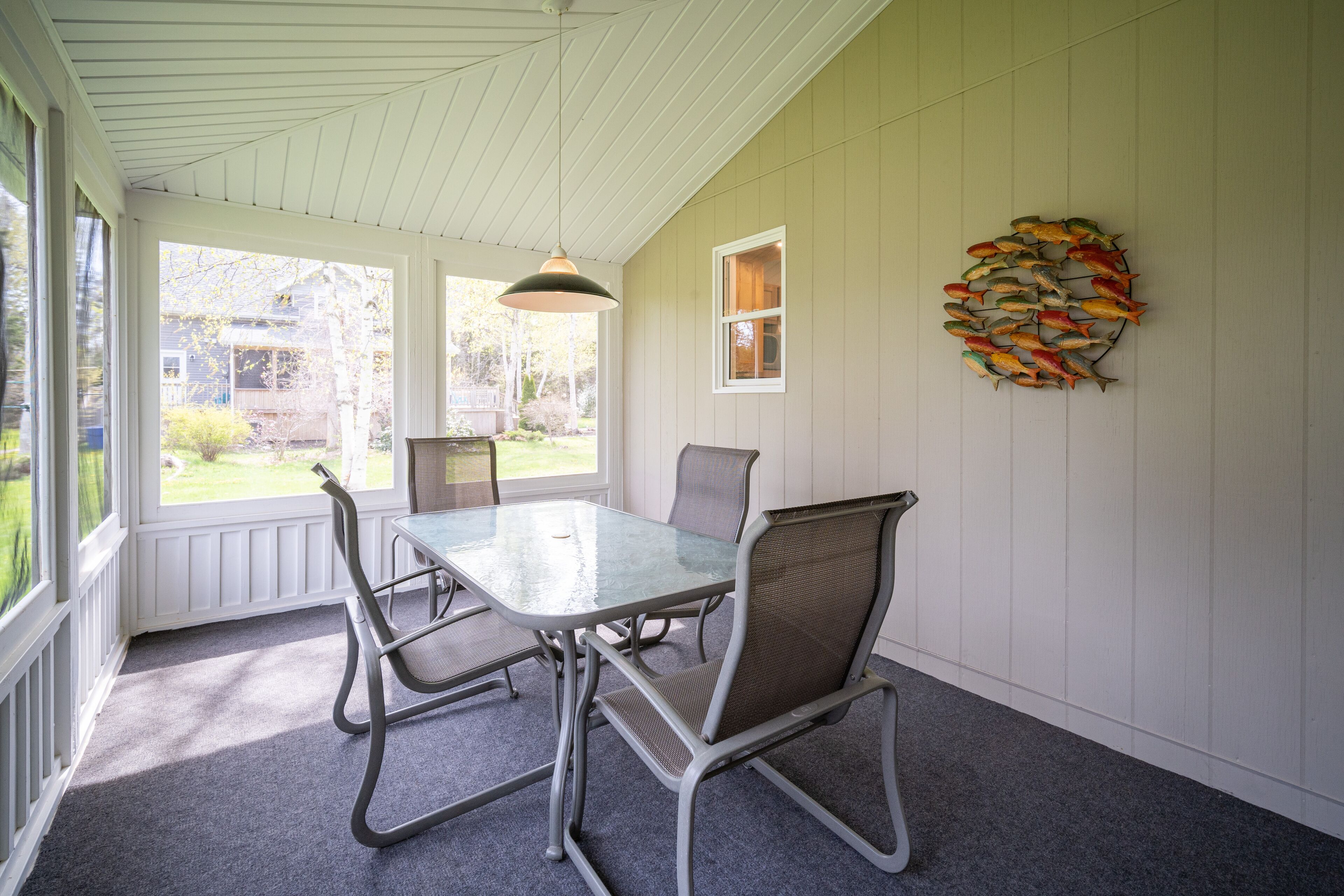 A dining area with a table and chairs, a hanging light fixture, and a wall decoration of fish.