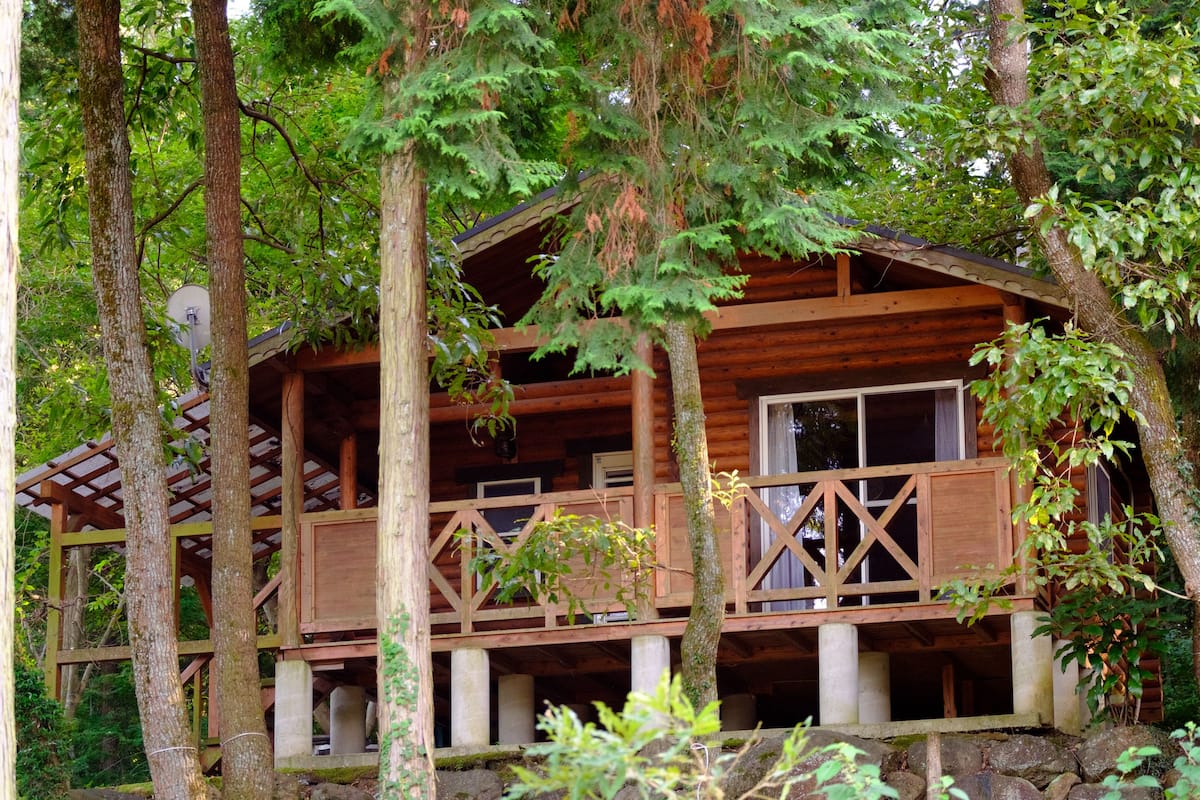 Eine Holzhütte mit Balkon, umgeben von Bäumen.