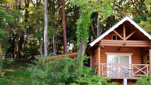 Uma cabana de madeira com varanda, rodeada por uma floresta densa.
