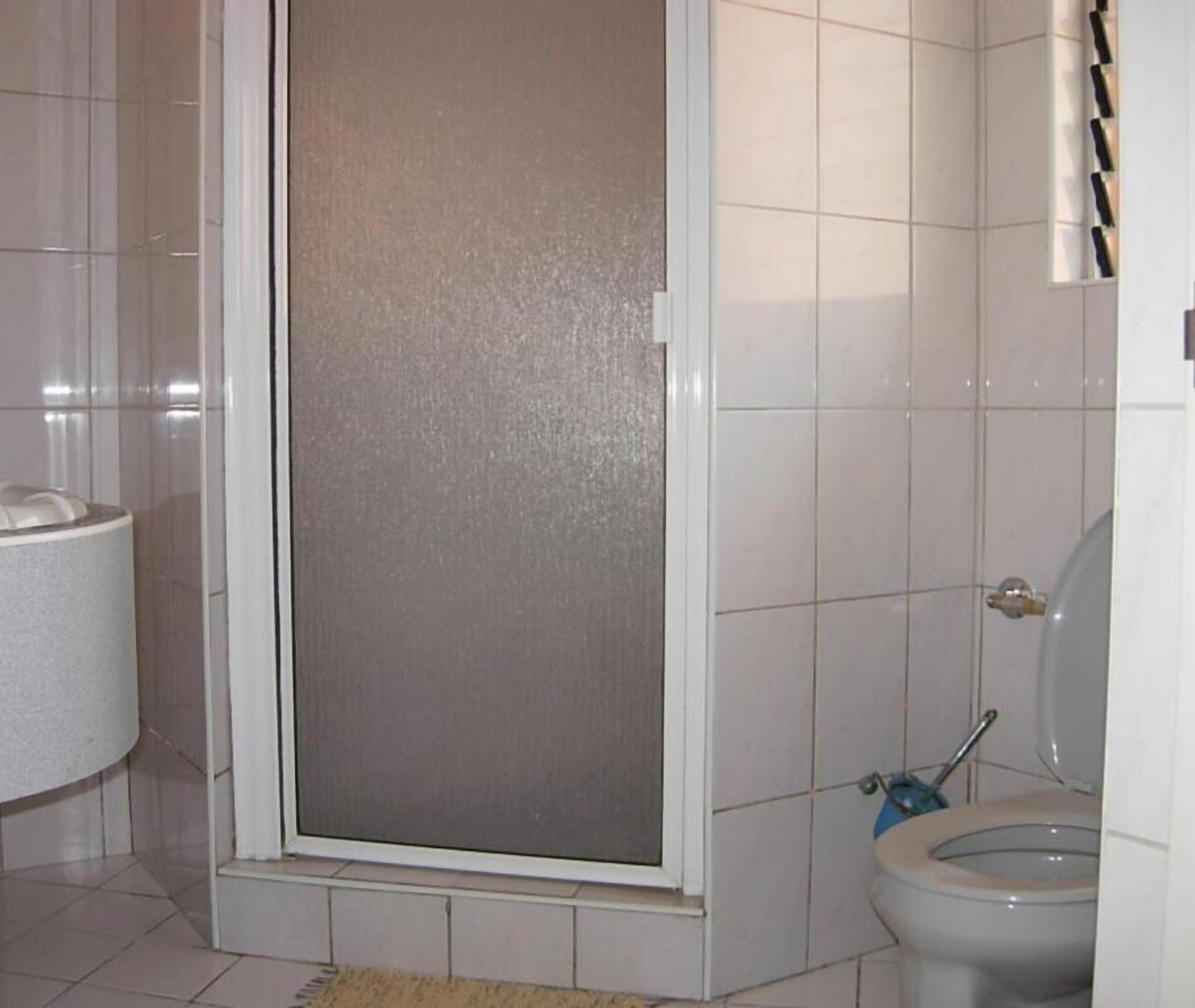 Casa de banho com chuveiro, sanita e porta-toalhas.