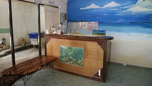 A room with a wooden bench, a wall clock, a calendar, and a beach mural. - Blue Coral Resort Boracay (Boracay Island)
