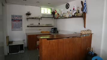 Un rincón de bar pequeño y acogedor con un mostrador de madera, estantes con diferentes botellas y banderas en la pared.