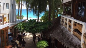A beachside courtyard with a thatched-roof hut, palm trees, and a view of the ocean. - Blue Coral Resort Boracay (Boracay Island)