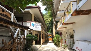 A narrow alleyway with a sign for Blue Coral Resort, wooden structures, and a parked vehicle. - Blue Coral Resort Boracay (Boracay Island)