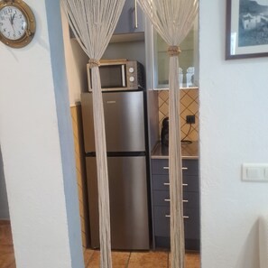 A kitchen with a refrigerator, microwave, and a clock on the wall.