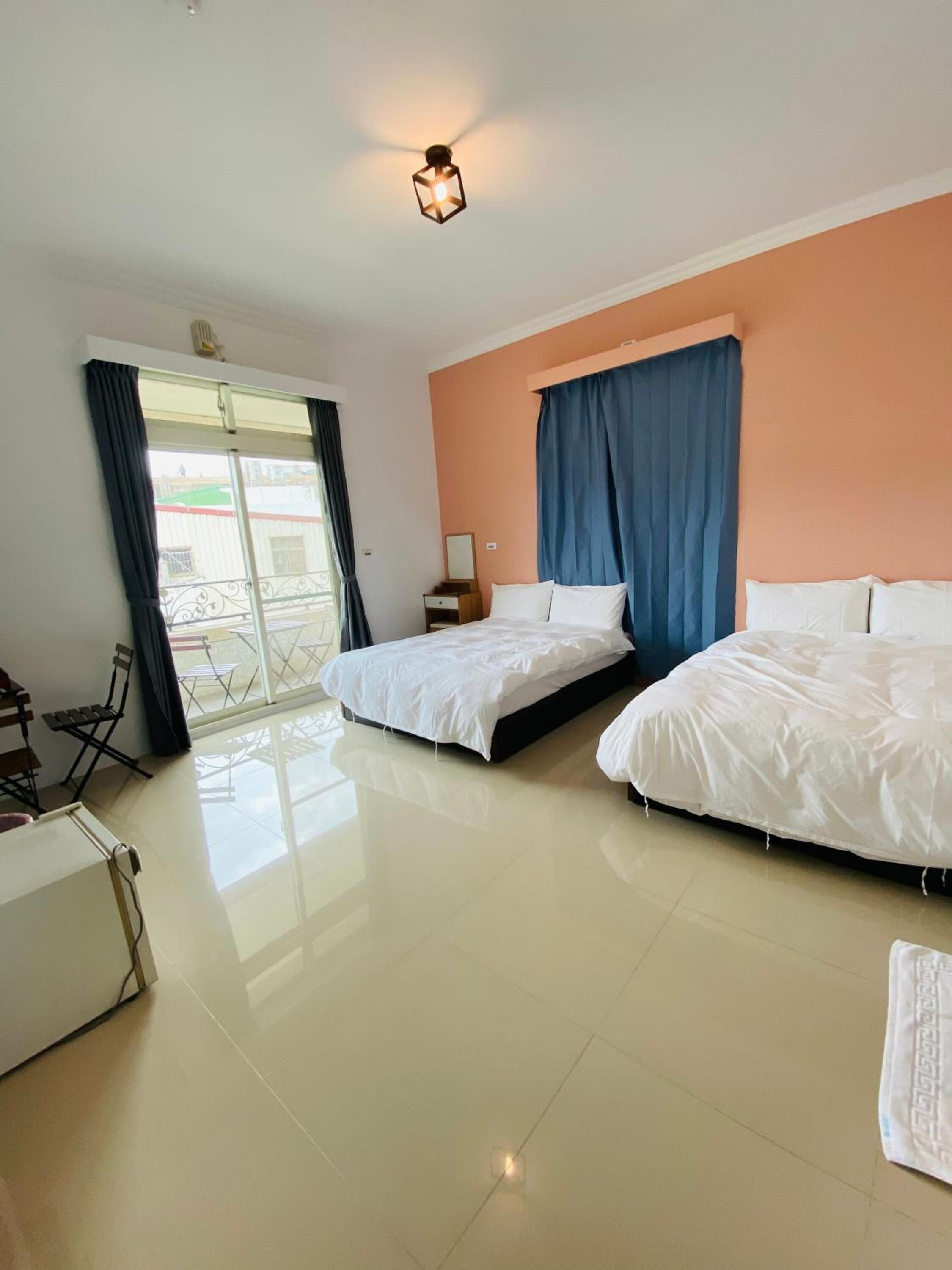 Habitació d'hotel amb dos llits, una taula de treball i un balcó.