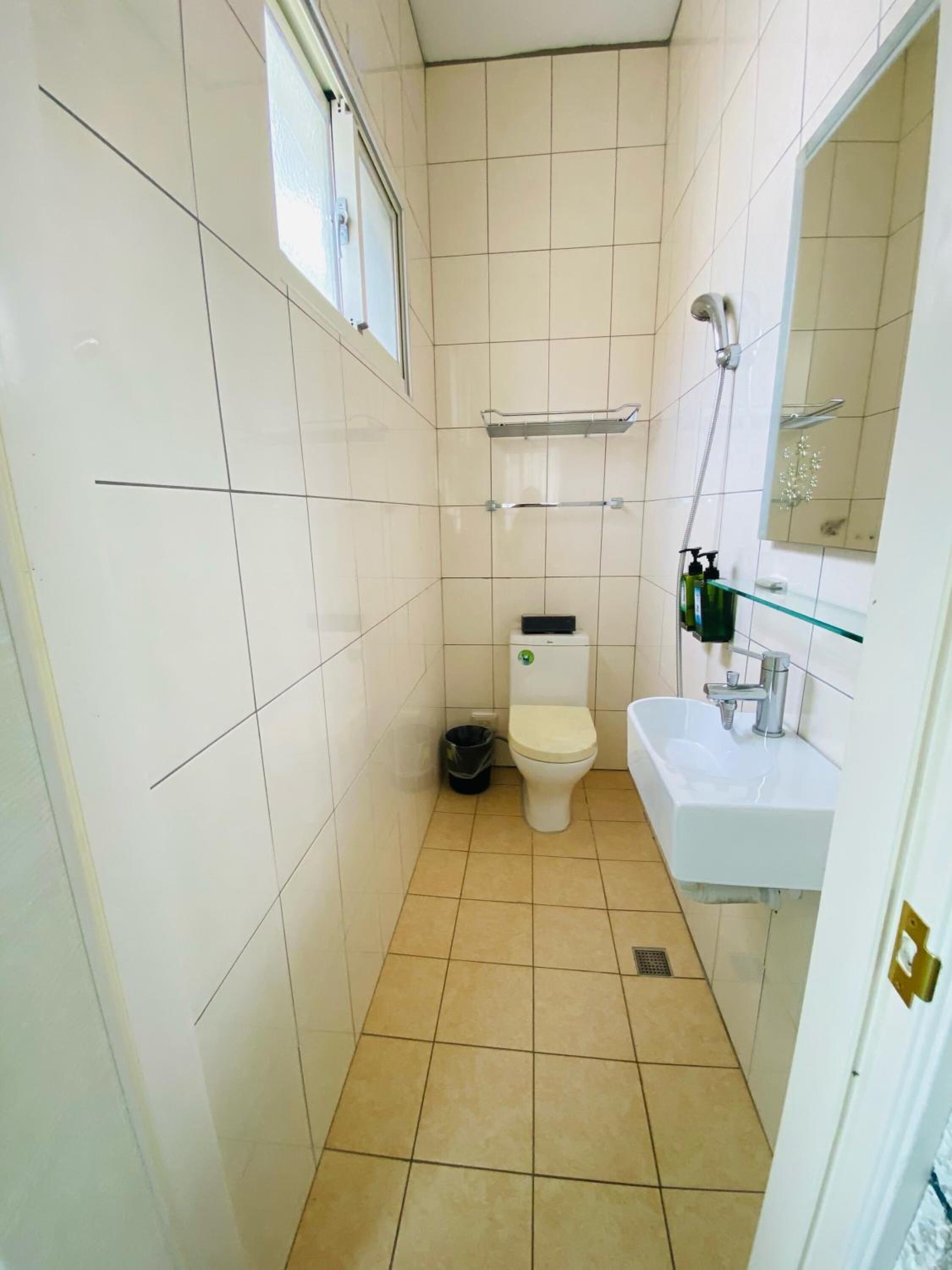 Un baño pequeño con azulejos, un inodoro, un lavabo y una ducha.