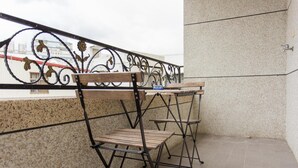 A balcony with a wrought iron railing, a wooden bench, and a small table. - Vicky House (Hualien City)