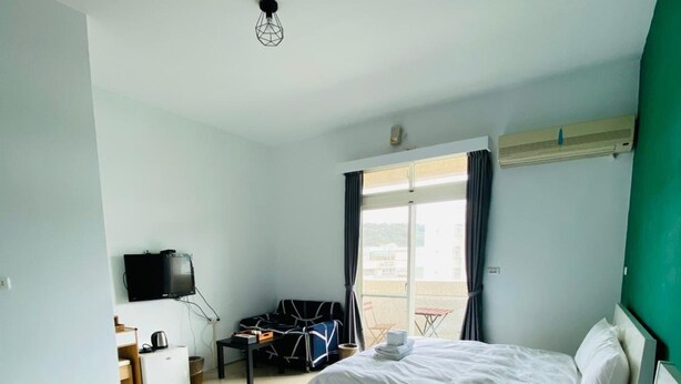 A hotel room with two beds, a TV, a desk with a computer, and a window with curtains. - Vicky House (Hualien City)