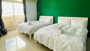 A hotel room with two beds, a green wall, and a sliding glass door to the balcony. - Vicky House (Hualien City)