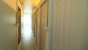 A narrow hallway with white doors on one side and a tiled floor. - Krit Hostel (Bangkok)