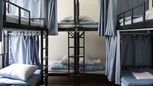 A bunk bed room with curtains, a ladder, and a window. - Krit Hostel (Bangkok)