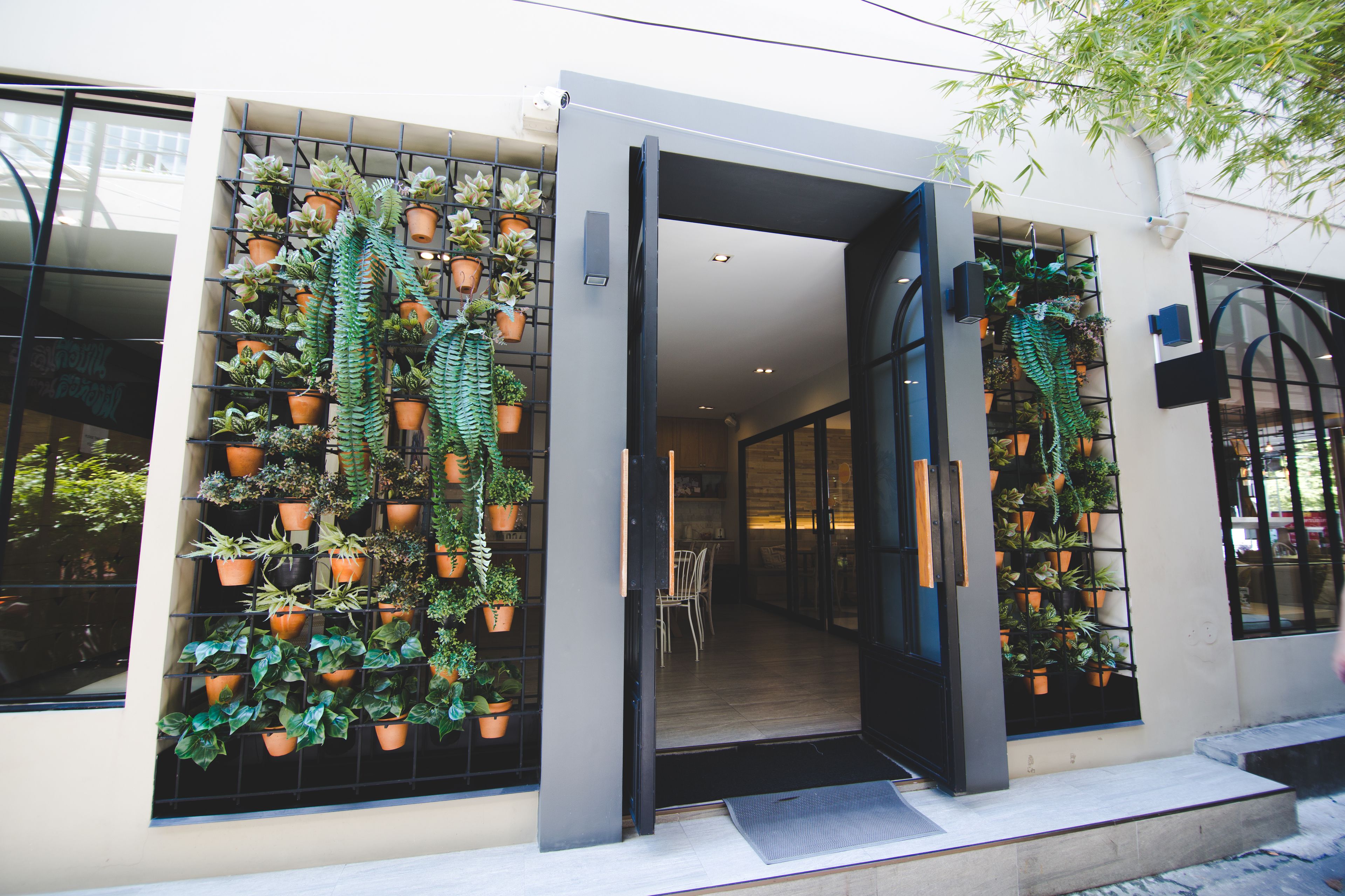 A building with a modern entrance, large windows, and a wall-mounted plant display.