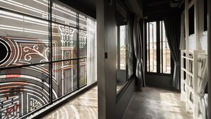 A modern hotel corridor with large windows, a patterned wall, and a view of the outside. - Issara by d Hostel (Bangkok)