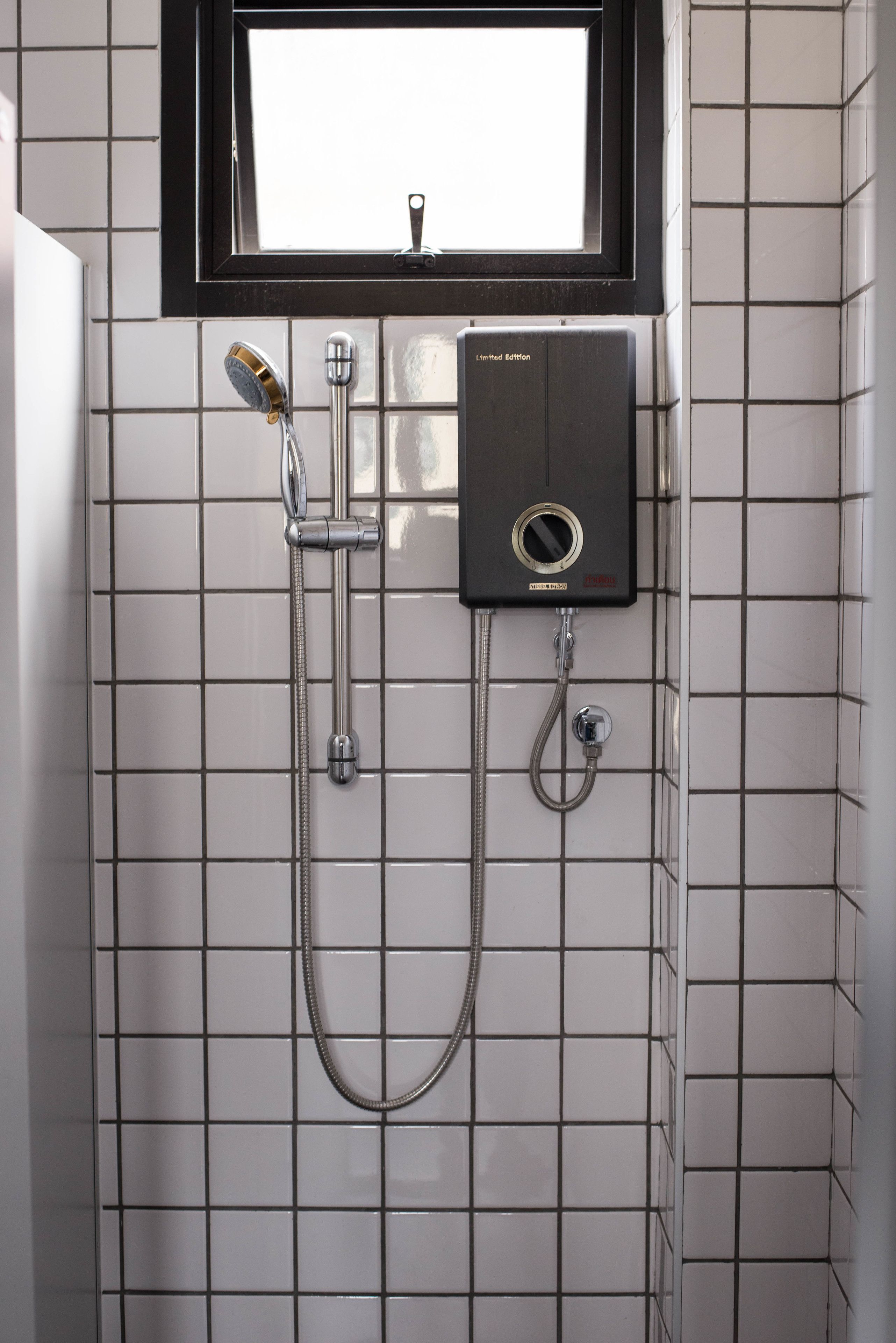 A bathroom with a shower, a window, and a wall-mounted heater.