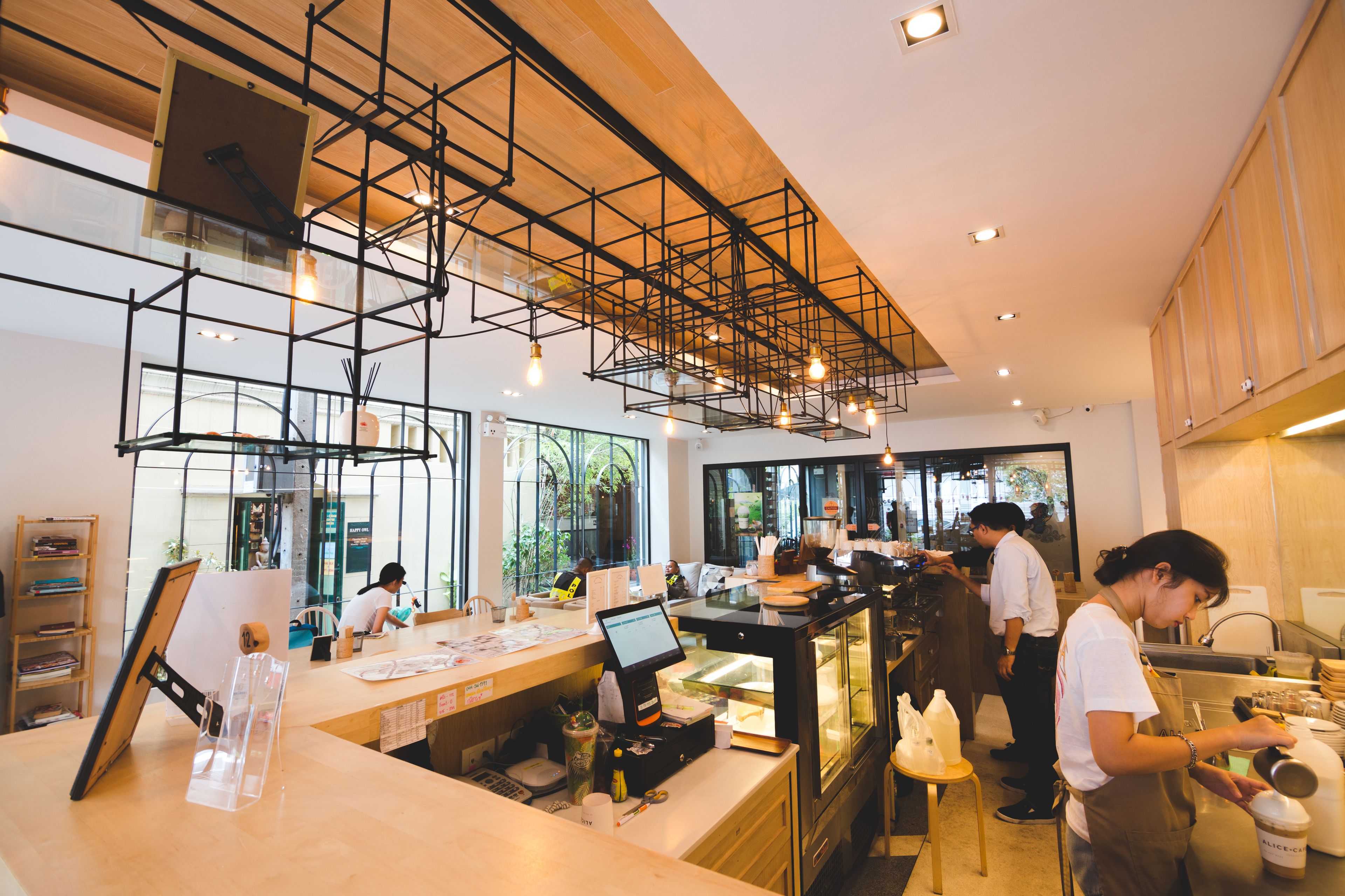 Een modern café interieur met houten balken, een toonbank met digitaal scherm en een glazen vitrine.