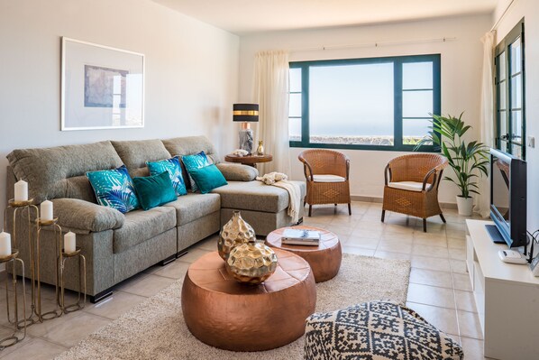 A living room with a sofa, two round coffee tables, a television, and a window with a view. - Luxury villa, swimming pool, sea views, A/C, BBQ, WIFI, (Tías)