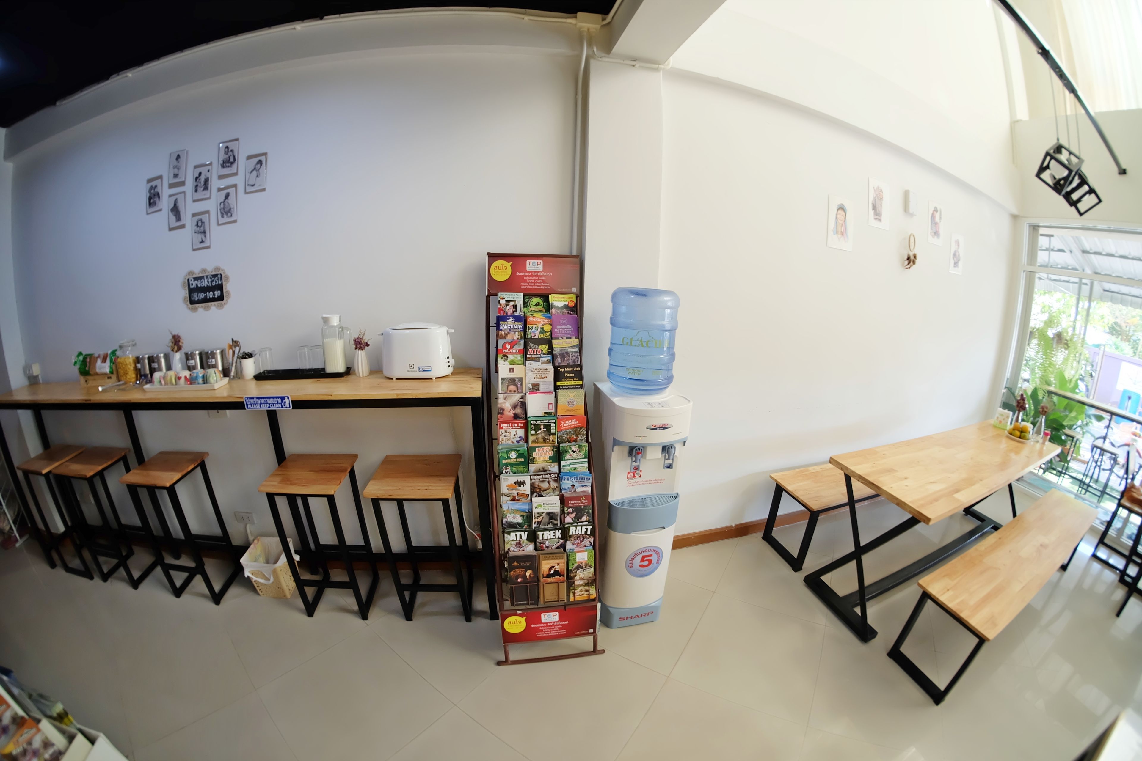 Ett café med träbord och barstolar, en vattenautomat och en menytavla.