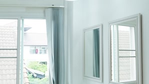 Un baño con dos lavamanos, una ventana con cortinas y una lámpara en el techo.