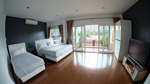 Habitación de hotel con dos camas, televisión y balcón con vista a la ciudad.