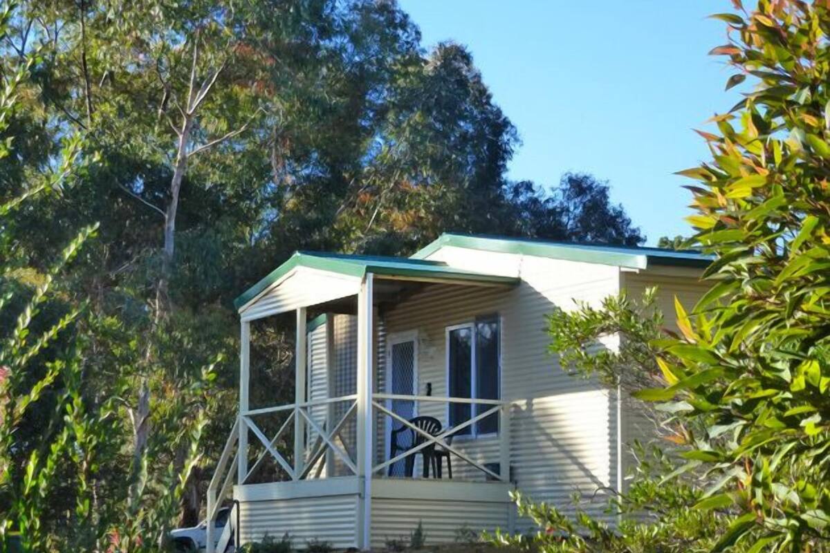 A single-story house with a porch, surrounded by trees.