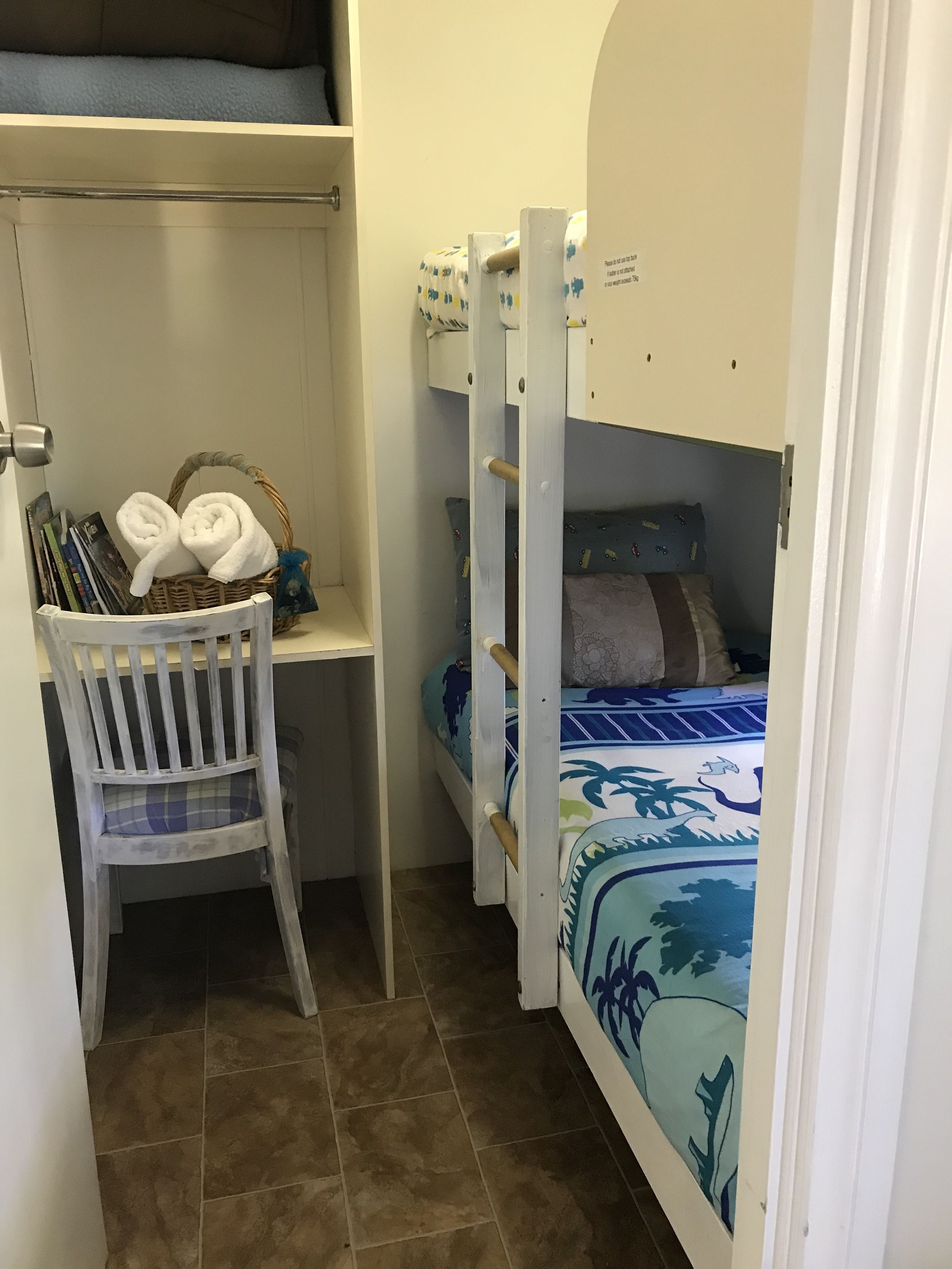 Una habitación compacta con una cama litera, un escritorio con silla y un armario pequeño.