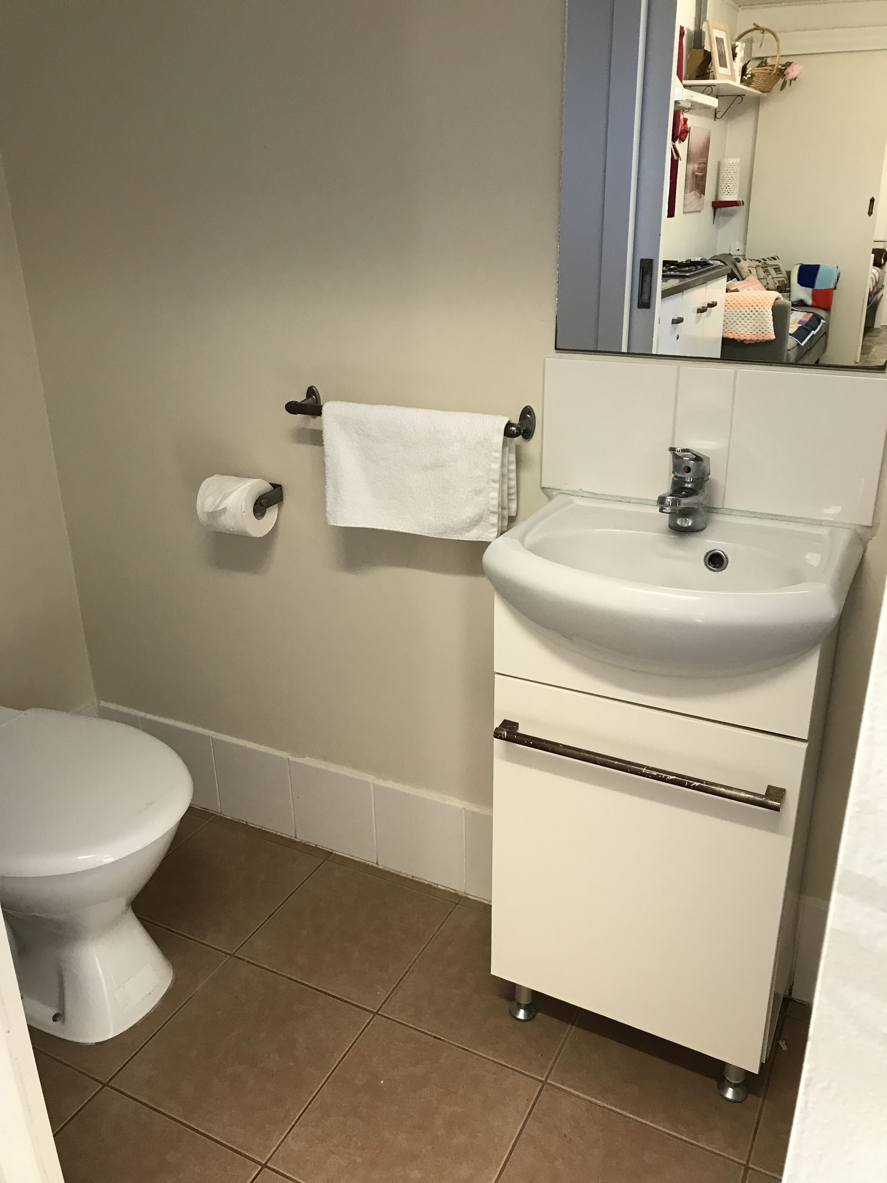 A bathroom with a toilet, sink, and towel rack.