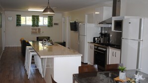 A modern kitchen with a central island, white cabinetry, and stainless steel appliances. - Padthaway Caravan Park (Padthaway)