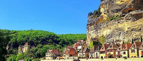 A riverside town with historic buildings, a prominent castle, and a steep cliff.