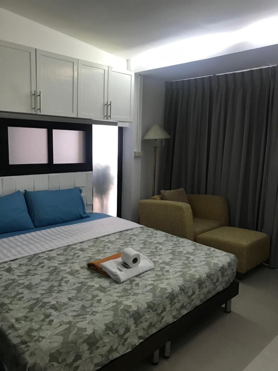 Une chambre d’hôtel avec un lit, un canapé, une lampe et une fenêtre avec des rideaux.