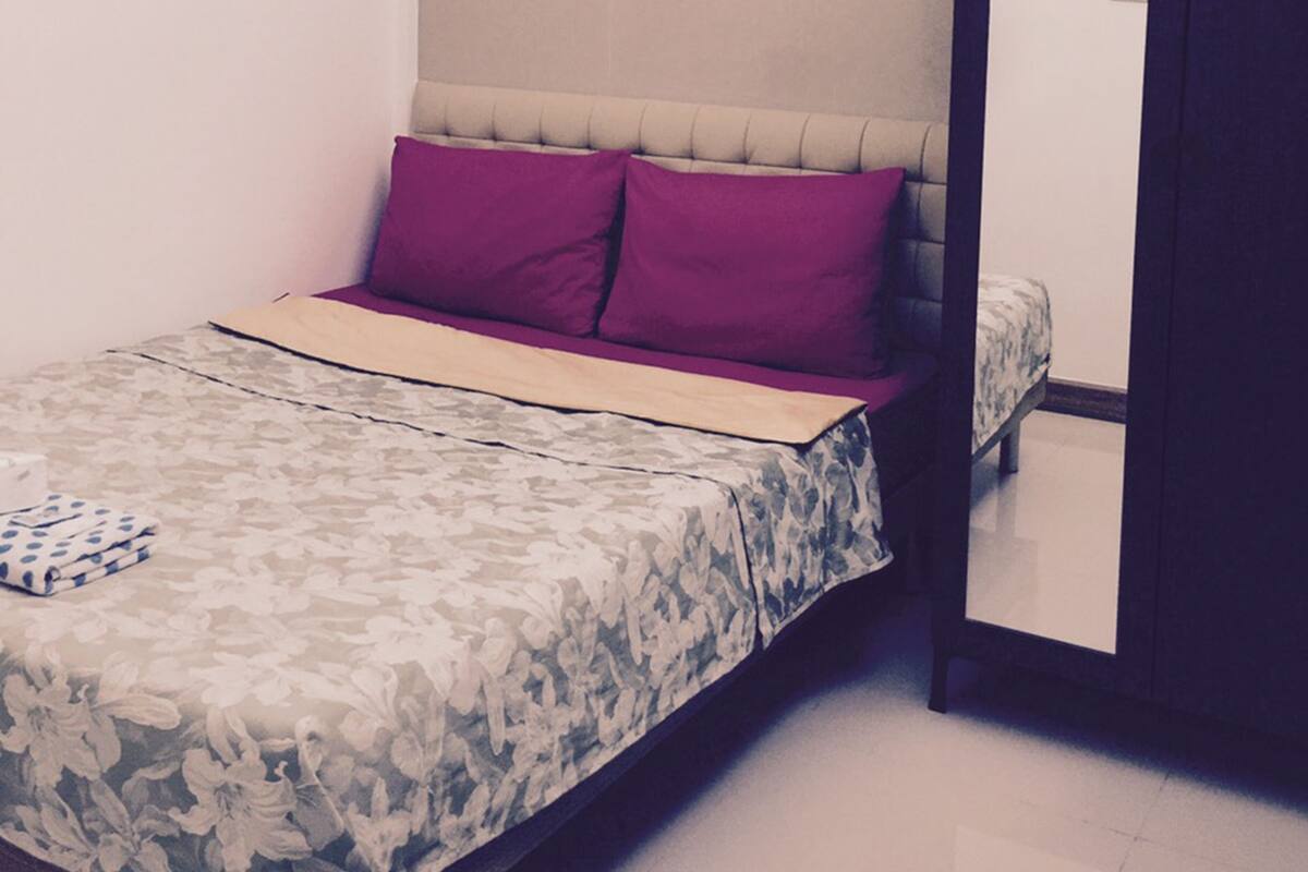 A bedroom with a bed, a headboard, a nightstand, and a wardrobe.