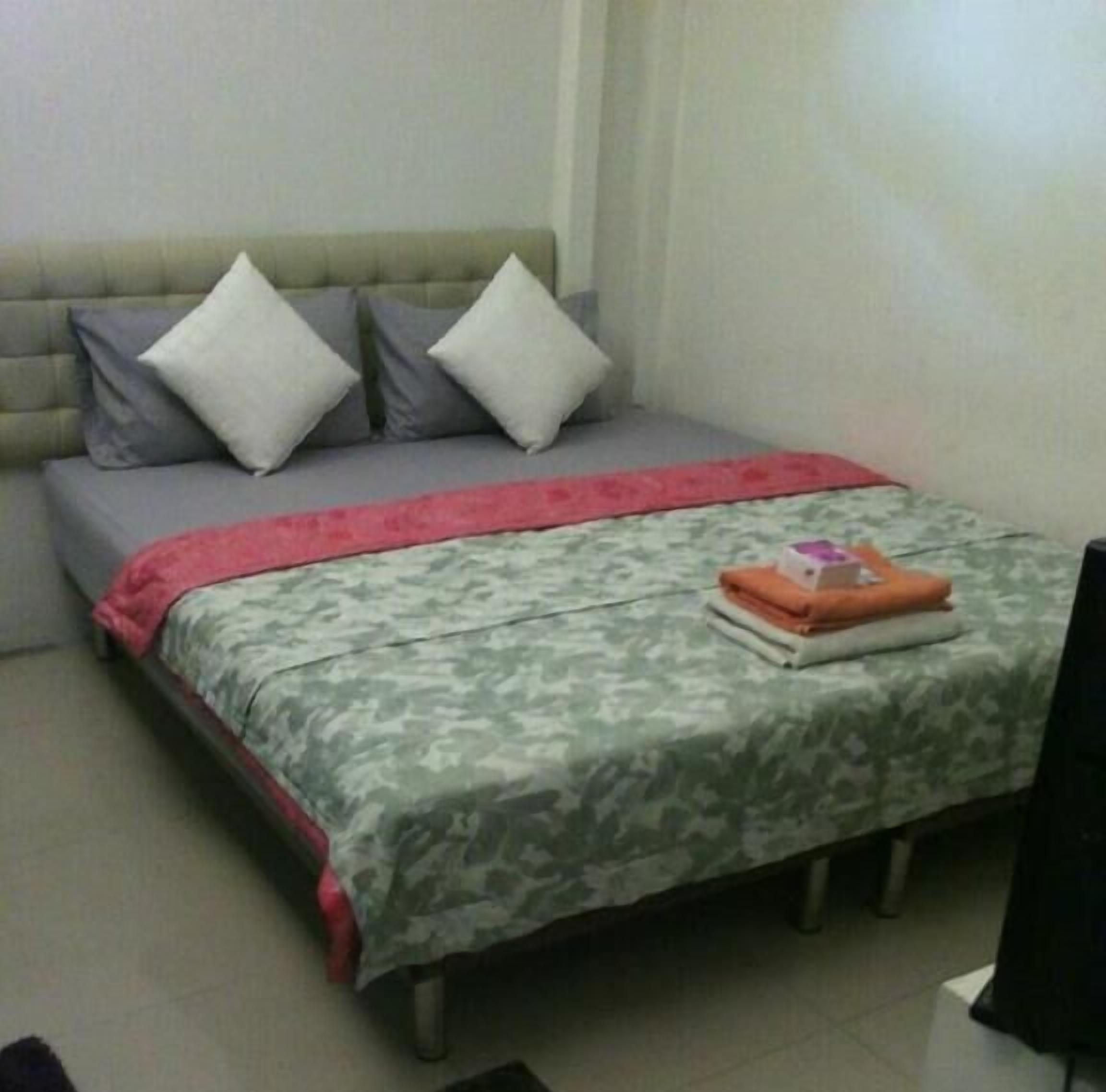 A bedroom with a bed, pillows, a blanket, and a folded towel on the bed.