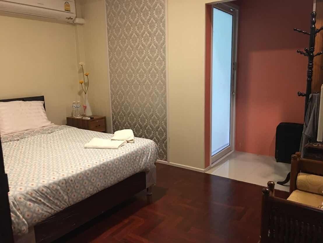 Un dormitorio con una cama, una mesita de noche, una silla, una ventana y una puerta.